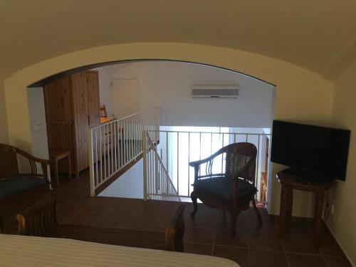 Habitación con escalera, silla y TV. en Apartament Riera, en Cadaqués