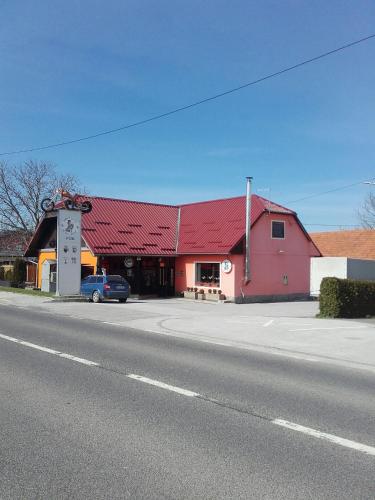 a red building with a red roof next to a street at apartma "happy Scotts" in Starše