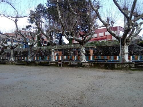 a fence with trees in front of a building at Ático con vistas a la ría de Arosa in Rianjo
