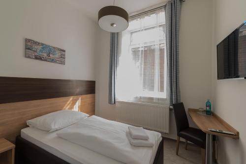 a bedroom with a bed and a desk and a window at Boutique-Hotel Kronenstuben in Ludwigsburg