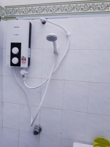 a shower in a bathroom with a hose on the wall at TSA Jitra Homestay in Kampong Pantai Halban