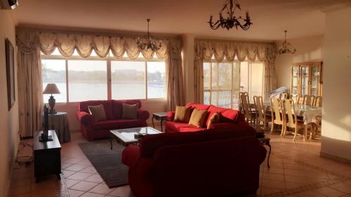 a living room with red couches and a dining room at Durat Alarous Apartment in Durat Alarous