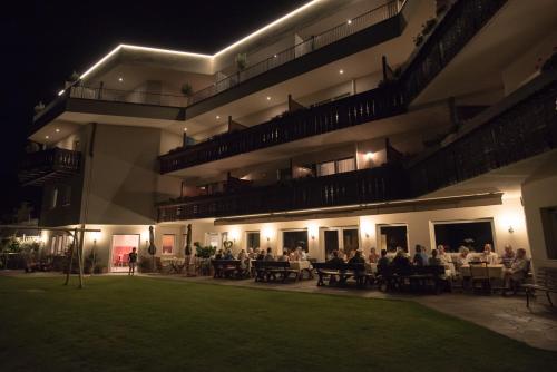 a group of people sitting at tables in a building at night at Hotel Garni Herz in Tirolo