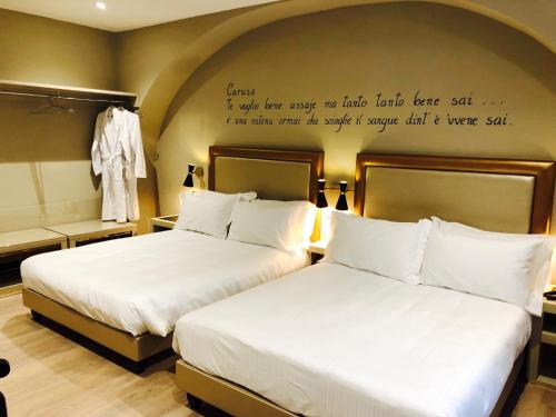 two beds in a hotel room with a quote on the wall at Caruso Place Boutique & Wellness Suites in Naples