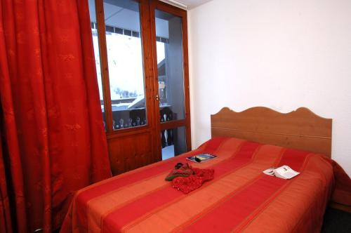 a bedroom with a red bed with two stuffed animals on it at Résidence Odalys Les Hauts du Rogoney in Val dʼIsère