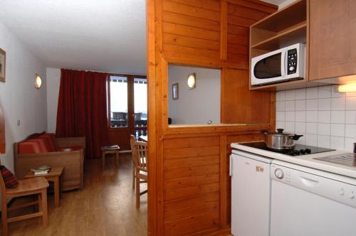 a kitchen with a stove and a microwave at Résidence Odalys Les Hauts du Rogoney in Val dʼIsère