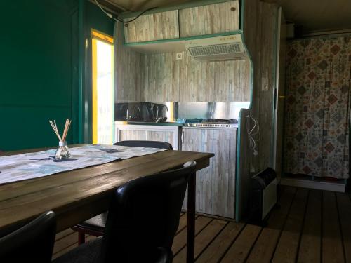 a kitchen with a wooden table with chairs and a stove at Boerderijcamping de Kreitsberg in Zeeland