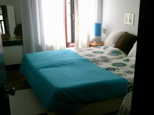 a bed with a blue comforter in a bedroom at Apartment Troia Garden in Troia