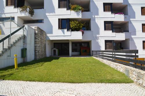 a building with a grass yard in front of it at Amazing Beach & Pool Apartment with Garden in Sesimbra