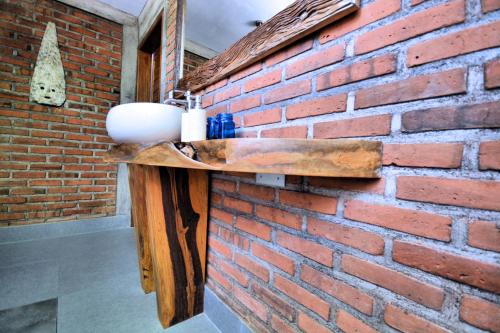 a brick wall with a wooden shelf on it at Coco Garden Pool Villas in Kubutambahan