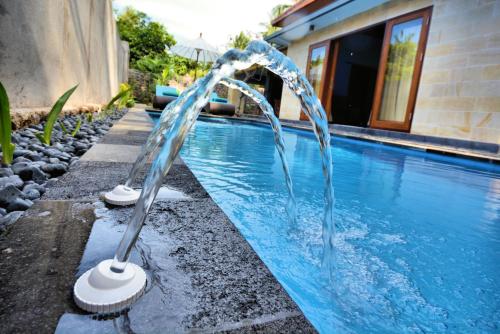 a pool with two water fountains in front of a house at Coco Garden Pool Villas in Kubutambahan