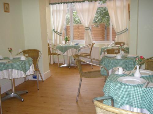 ボーンマスにあるイングルデン ゲストハウスのテーブルと椅子(緑と白のテーブルクロス付)のあるレストラン