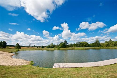 a large pond with a wooden walkway in a field at Tawerna-Stawiska in Garbatka-Letnisko