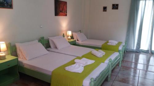 two beds in a room with green and white at Pitsinis Studios & Apartments in Roda