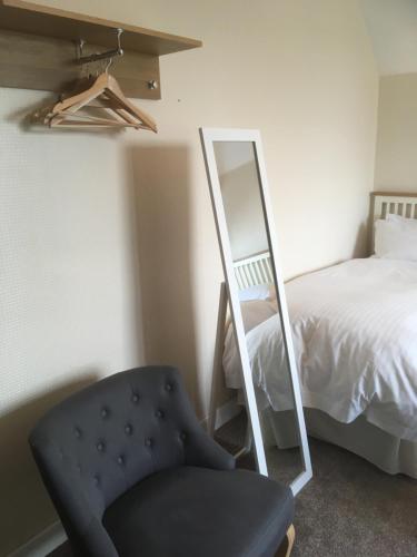 a bedroom with a mirror and a chair and a bed at Elmdon Lodge in Birmingham
