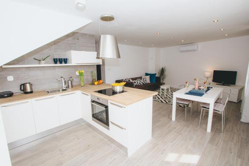 a kitchen with white cabinets and a table and a dining room at Šuština in Tribunj