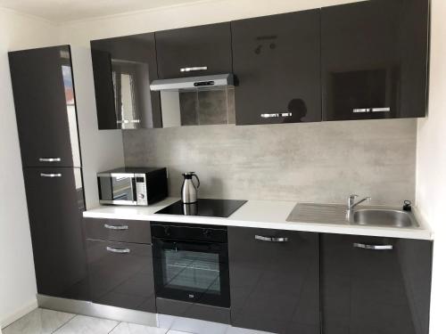 a kitchen with black cabinets and a sink at Les Charmantes in Cernay