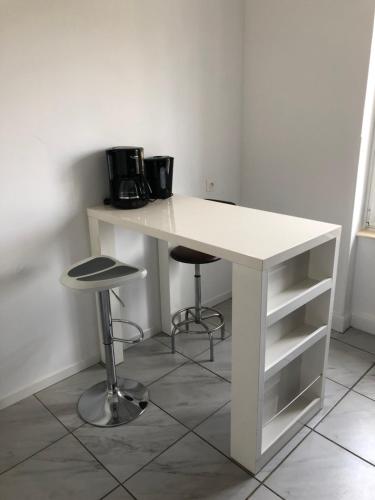 a white desk with two stools and a microwave at Les Charmantes in Cernay