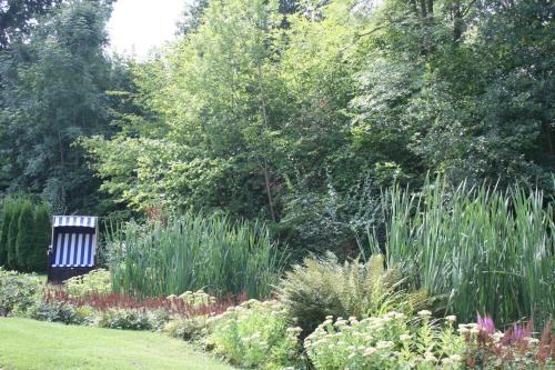 a park bench in a garden with flowers and trees at Hotel Muschinsky in Bad Lauterberg