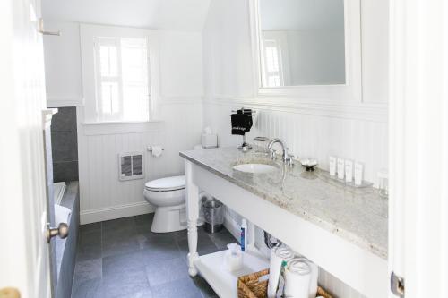 a white bathroom with a toilet and a sink at The Platinum Pebble Boutique Inn - Adults Only Property in Harwich Port