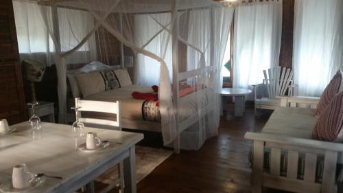 a bedroom with a bed and a table and chairs at Pura Vida Lodge in Morrumbene