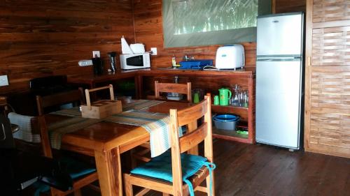 a kitchen with a wooden table and a refrigerator at Pura Vida Lodge in Morrumbene