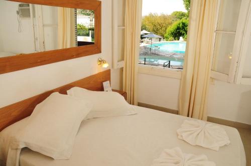1 dormitorio con cama con espejo y ventana en Hostal de la Costa en Villa Carlos Paz