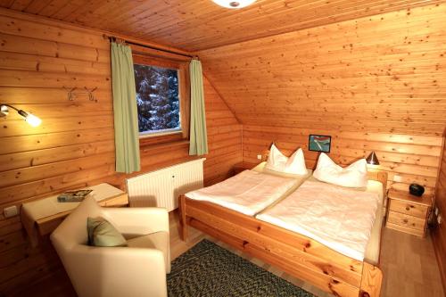 ein Schlafzimmer mit einem Bett und einem Stuhl in einer Hütte in der Unterkunft ****FH Blauvogel 60 Harz in Hasselfelde