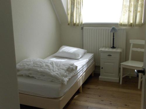 ein kleines Schlafzimmer mit einem Bett und einem Stuhl in der Unterkunft de Paardenmarkt in Aardenburg