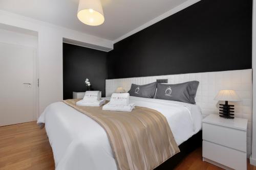 a bedroom with a large white bed with black walls at The Queen Luxury Apartments - Villa Carlotta in Luxembourg