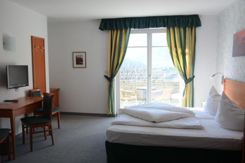 a hotel room with a bed and a desk and a window at Hotel Tannerhof in Schenna