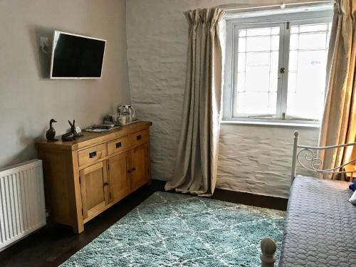 a bedroom with a wooden dresser and a window at The Slipway in Port Isaac