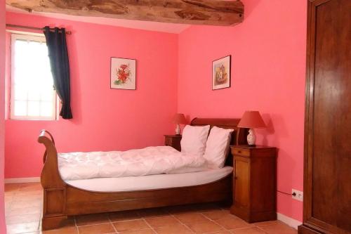 une chambre avec un lit avec un mur rose dans l'établissement Le Douitel, à Roncey
