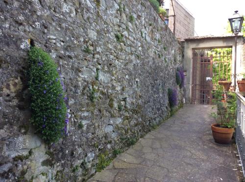 an alley with a stone wall with purple flowers at Casa Vacanze Amelia in Fiesole