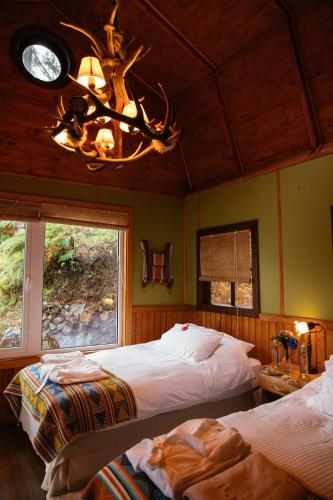 a bedroom with two beds and a chandelier at Barraco Lodge in Puelo