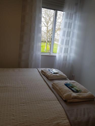 a bed with two pillows in front of a window at Casa de Campo Cruz de Pedra in Portomarin