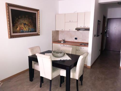 a kitchen with a black table and white chairs at Beach Apartment in Rafailovici