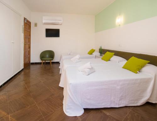 two beds in a white room with green pillows at Hostal Alicante in San Antonio