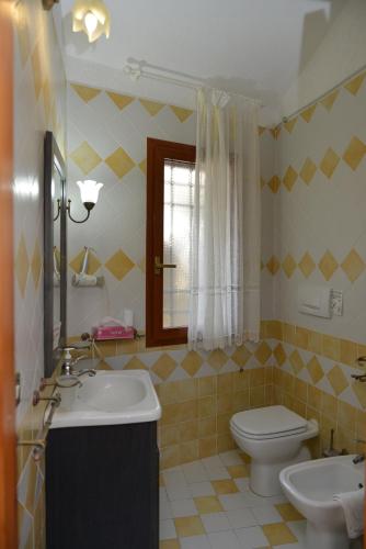 a bathroom with a sink and a toilet and a window at La Fonte dell'ulivo 3 in La Maddalena