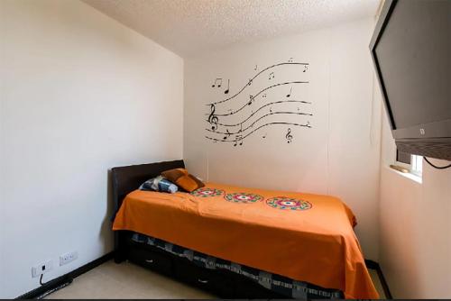 1 dormitorio con 1 cama con notas musicales en la pared en Apartasol en Santa Fe de Antioquia