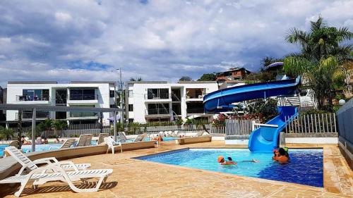 a pool with a slide and people in the water at Apartasol in Santa Fe de Antioquia