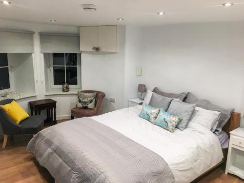 a bedroom with a large white bed and a chair at Garden Apartment in Grange Over Sands