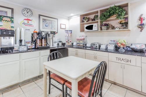 a kitchen with white cabinets and a table and chairs at Super 8 by Wyndham St. Charles in Saint Charles