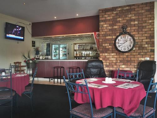 Ceduna Motor Inn في سيدونا: غرفة طعام مع طاولات وساعة على الحائط