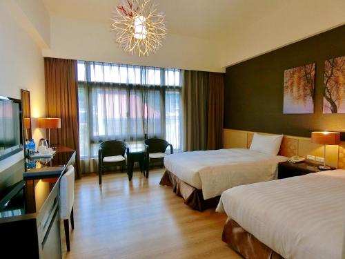 a hotel room with two beds and a desk and a television at LeaLea Garden Hotels - Moon Lake in Yuchi
