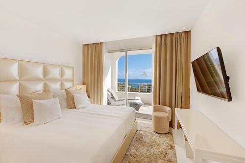a bedroom with a bed and a window with the ocean at Portals Hills Boutique Hotel in Portals Nous