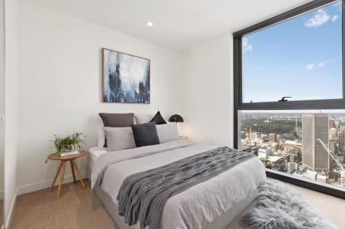 um quarto com uma cama e uma grande janela em Luxuria Apartments - EQ Tower em Melbourne