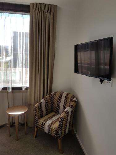 a living room with a chair and a flat screen tv at Wyndham Garden Remarkables Park Queenstown in Queenstown