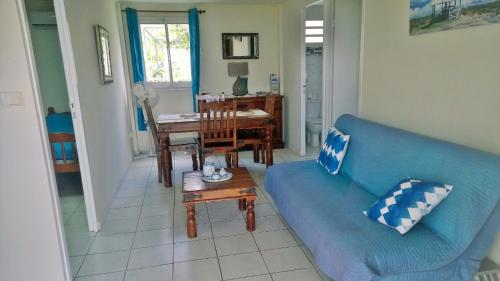 a living room with a blue couch and a table at Les Bungalows du Mont-Auban in Sainte-Clotilde