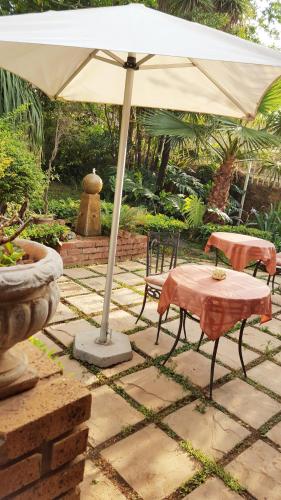 a table and chairs under an umbrella on a patio at Amper Bo Guest House in Pretoria